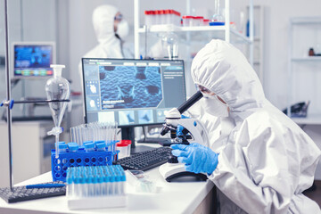 Team of medical personal wearing ppe suit doing coronavirus analysis in modern laboratory. Chemist...