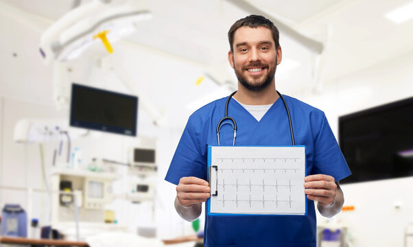 medicine, healthcare and surgery concept - happy smiling doctor or male nurse in blue uniform with cardiogram on clipboard over operating room at hospital background