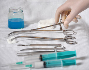 On a white background are medical instruments, syringes, a gloved hand holding a clip. The...