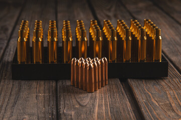 Heavy bullets for hunting and prepared casings on a wooden background, ammo reloading, soft focus - obrazy, fototapety, plakaty