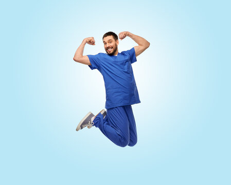 healthcare, profession and medicine concept - happy smiling doctor or male nurse in uniform jumping in air over blue background