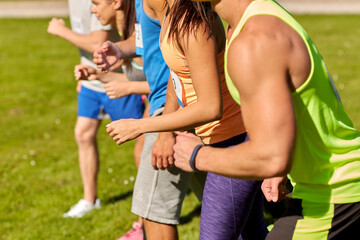 fitness, sport, race and healthy lifestyle concept - group of friends or sportsmen with badge numbers on start of running marathon outdoors