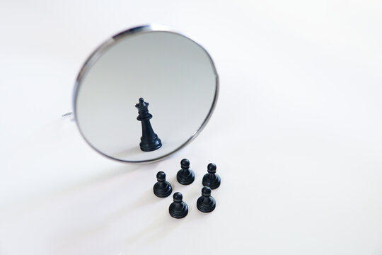 A chess piece in front of mirror with reflection. Concept of business leadership teamwork power and belief