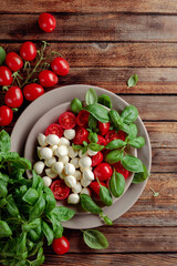 Caprese salad with tomato, mini mozzarella and basil on a old wooden table.