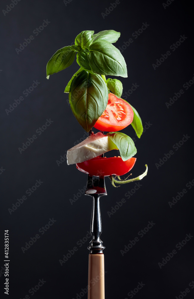 Wall mural Mozzarella with tomato and basil on a fork.