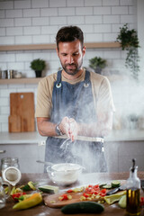 Happy man baking in the kitchen. Man making delicious food at home.