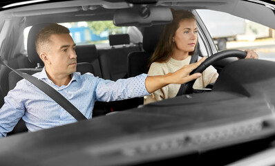 driver courses and people concept - car driving school instructor teaching young woman to drive