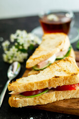 English sandwiches. Filling with tomato, dill and butter. The shape is triangular. A cup of tea is visible in the background. Blurred background. Copy space