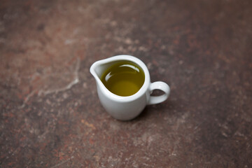 A small white porcelain jug with olive oil on the table.