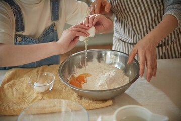 Happy adorable little child girl in apron enjoying cooking homemade pastry together with grandmother at home.