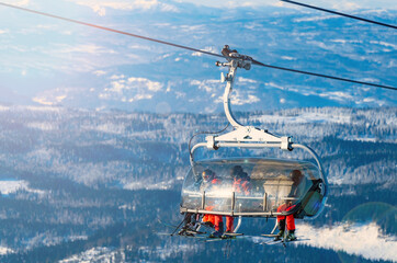 Group of skiers riding a ski lift to the top of a mountain at a ski resort.