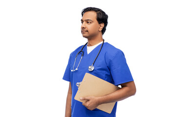 healthcare, profession and medicine concept - indian doctor or male nurse in blue uniform with clipboard and stethoscope over white background