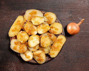 Baked potatoes with onion on a wooden background
