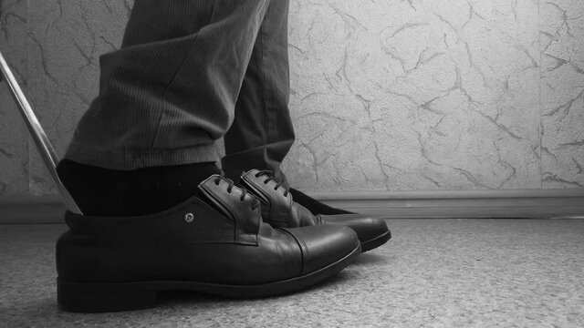 Man puts on shoes close-up. Monochrome 4K video.
