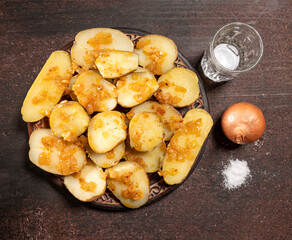  Baked potatoes with onion and a glass of vodka on a wooden background