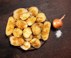 Baked potatoes with onion on a wooden background