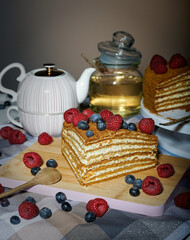 Selbstgemachte Honigtorte mit Beeren verziert. Eine Teekanne und ein Glas Honig stehen im...