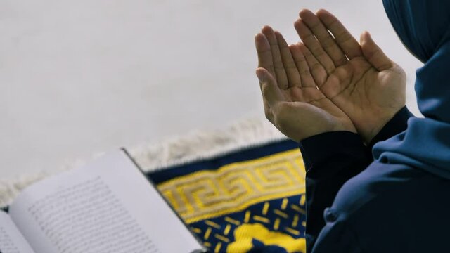 Muslim young woman in hijab is praying glorify Allah and practicing the Islamic faith in mosque.