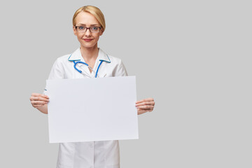 Female doctor holding a blank banner sign standing over grey background