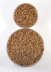 Two bowls with raw uncooked buckwheat. Top view. The texture of dry buckwheat. 