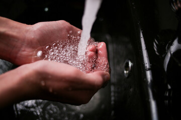 Crystal clear water with air bubbles pours into human hands