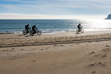 silhouette of three bikers cruising along a secluded beach with fat tire bikes