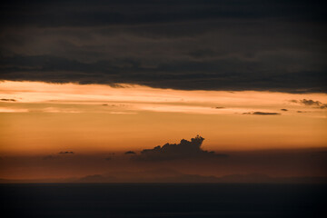 Fototapeta na wymiar beautiful view of clouds in orange sky above the ocean horizon line