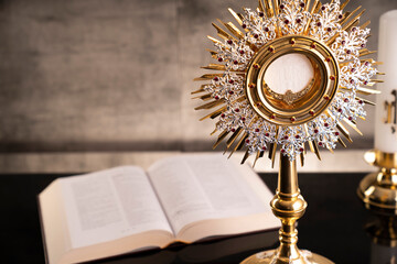 Catholic symbols composition. Religion concept. The Cross, monstrance,  Holy Bible and golden chalice gray background. 