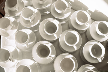 Lots of white cups for tea or coffee. Light background. View from above.