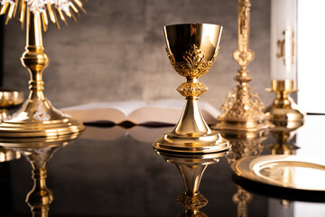 Catholic symbols composition. Religion concept. The Cross, monstrance,  Holy Bible and golden chalice gray background. 