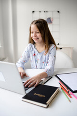 smiling schoolkid using laptop while doing schoolwork at home