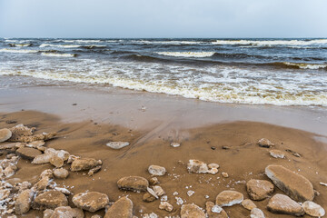 Winter Baltic Sea beach is snowy and there are big waves in the sea
