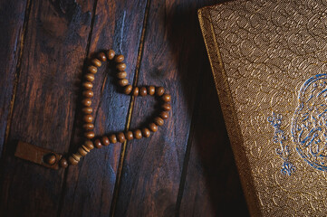 Holy book of Quran with rosary beads on wooden table 