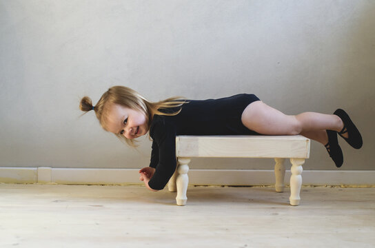 Funny little ballerina toddler does exercises at home. Little girl dreams of becoming a ballerina. Preparations for ballet or dance lessons. Hobbies for girl 