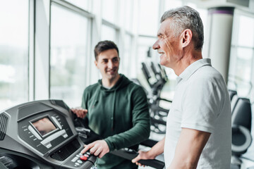 Close up in focus of an older man's face, he is looking ahead and performing a cardio exercise, in...