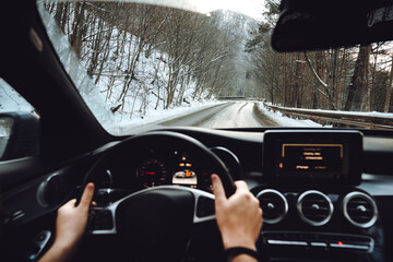 Caucasian male driving on forest road during wintertime. Snow and wet roads concept