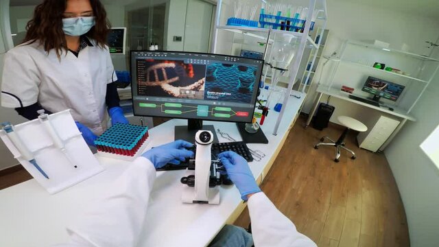 FPV of biotechnology scientist researching in laboratory using microscope analysing various bacteria. Chemist examining virus evolution using high tech for scientific research of vaccine development
