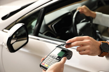 Man sitting in car and paying with credit card at gas station, closeup