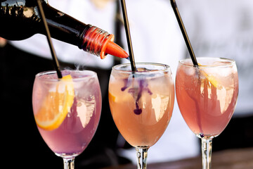 The process of making a pink cocktail with ice on a bar table.