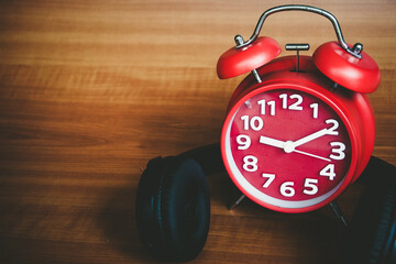 Retro alarm clock and headphone with wooden background