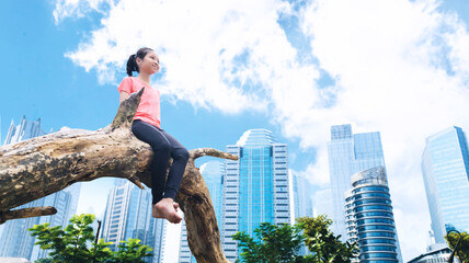 Lonely little girl sit on tree and look city view