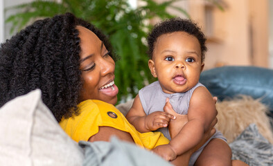Happy mother smiling and playing with her son at home.