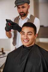 Attractive Caucasian hair stylist cleaning special hair instrument behind the delightful man...