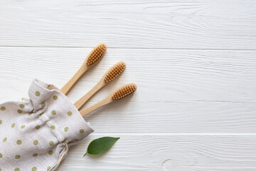 Wooden bamboo eco-friendly toothbrushes in a linen bag on a white wooden background with space for text. The concept of zero waste.