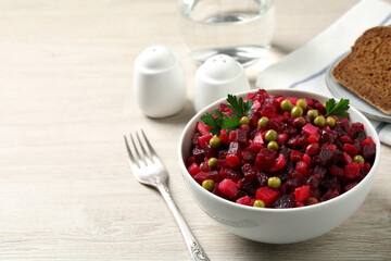 Traditional Russian salad vinaigrette served on white wooden table. Space for text