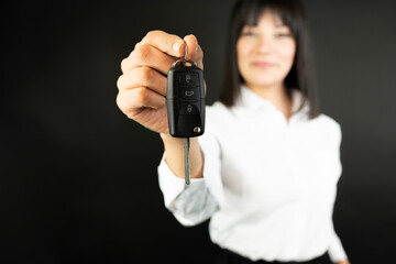 business woman hand with a car key. Isolated on black background