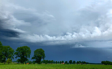 Threatening dark rainy clouds are covering a rural landscape, showing the Overcast and gloomy sky above the countryside creating a beautiful and impressive dramatic scenery