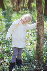 Beautiful little girl in a sunny spring forest..Glade of snowdrops. Easter time.