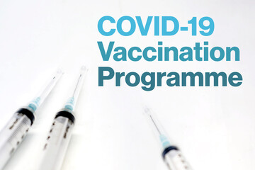 three syringes isolated on a white background and the text of the covid-19 vaccination programme