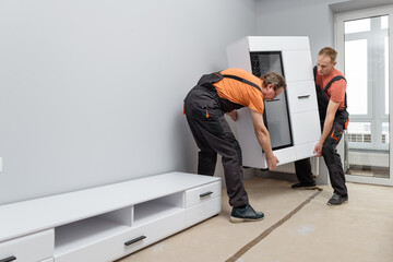 Workers move and install furniture in the apartment.